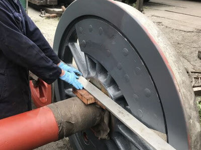 Pete holds the straight edge against the back of the wheel in order to measure the distance to the back of the wheel centre.